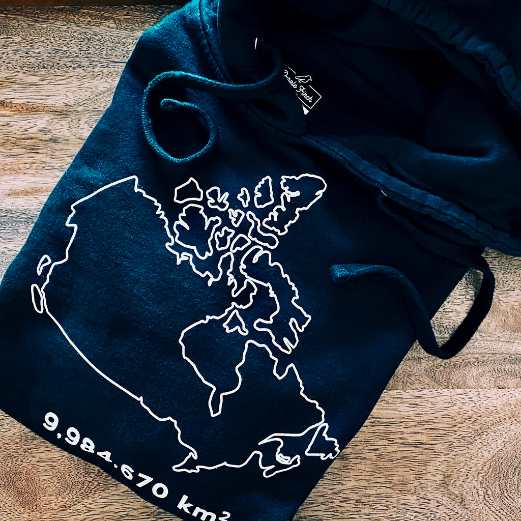 A picture of a black hooded sweatshirt with the country of Canada outlined in white. The number 9,984,670 appears underneath, as that is the number of square kilometres in Canada.
