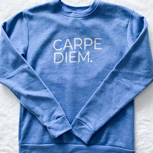 This long sleeved crewneck pullover is the colour of a clear blue sky. Screen printed on the front, in silver capital letters, are the words "Carpe Diem."