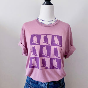 The image on this t-shirt has nine squares, three per row, of alternating purple and pink owls. The pink owl has a purple background, and the purple owl is in front of a pink background.