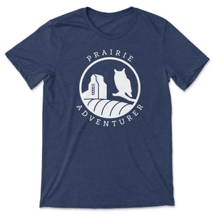 This navy t-shirt contains silhouettes in white of a grain elevator on the left and a Great Horned Owl on the right. The curve of a hay bail appears at the bottom of the graphic.