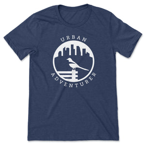 This navy t-shirt has a white silhouette of a magpie perched on a bench.  In the background is a city skyline.  